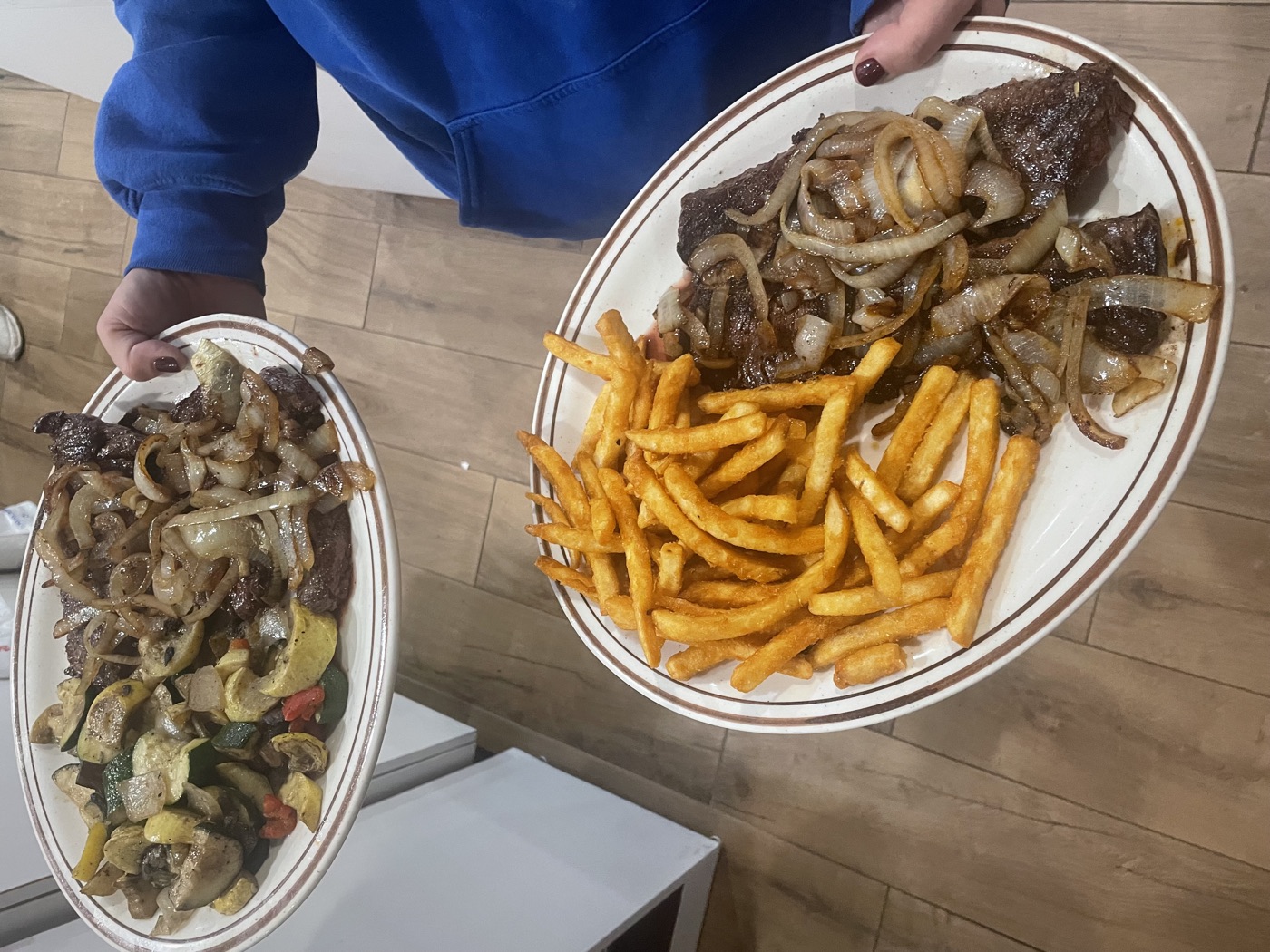 Steak platters with grilled onions, vegetables, and fries